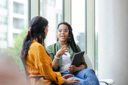 image of two women sitting in chairs conversing